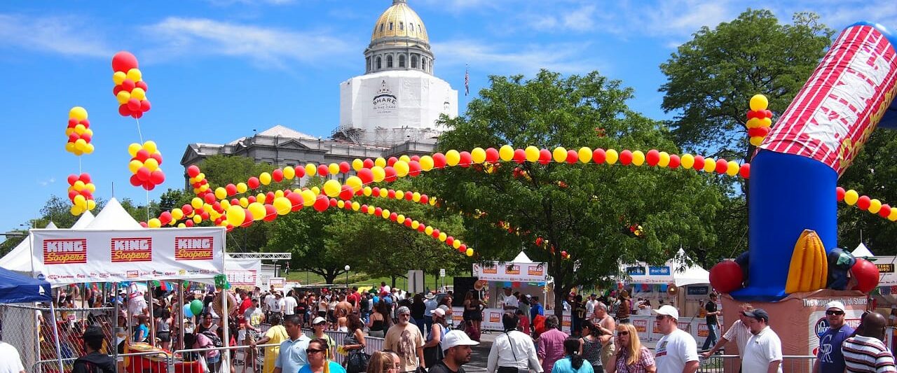 Cinco De Mayo Denver. Crowds of people on the street with yellow and red balloon arches going across the top