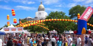 Cinco De Mayo Denver. Crowds of people on the street with yellow and red balloon arches going across the top