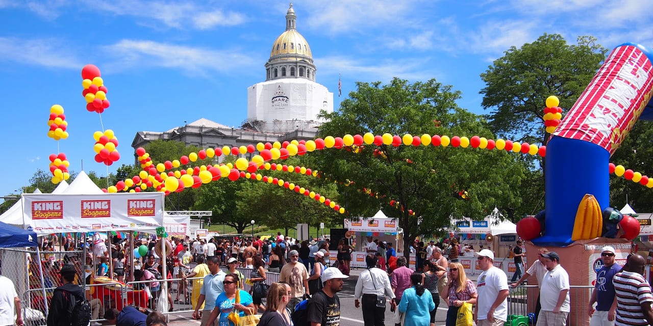 Cinco De Mayo Denver. Crowds of people on the street with yellow and red balloon arches going across the top