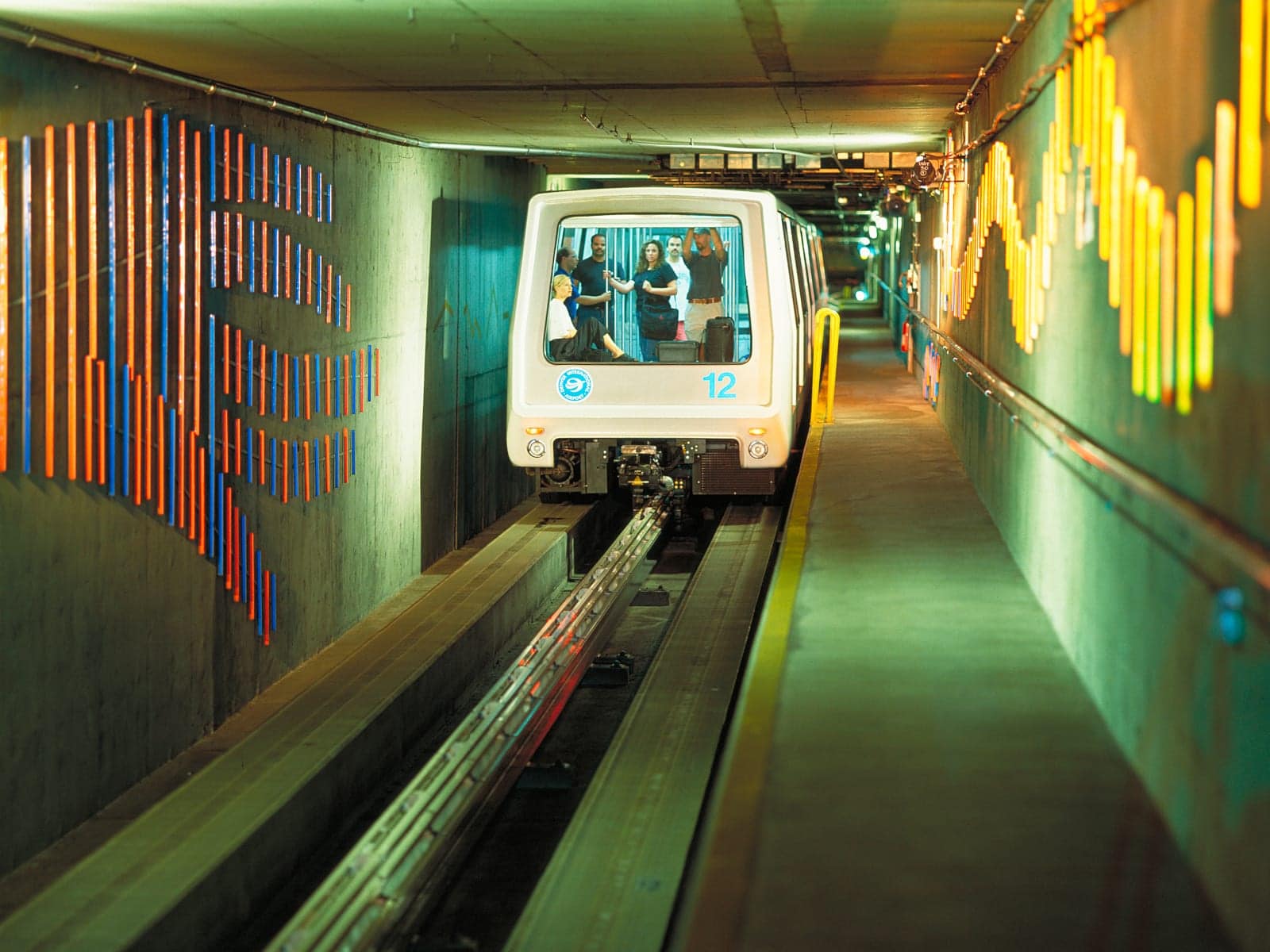 Denver Airport train going through tunnel with colorful murals on walls