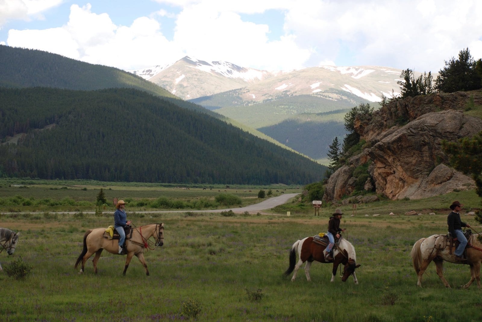 Image of people riding horses in a valley at Tumbling River Ranch, CO