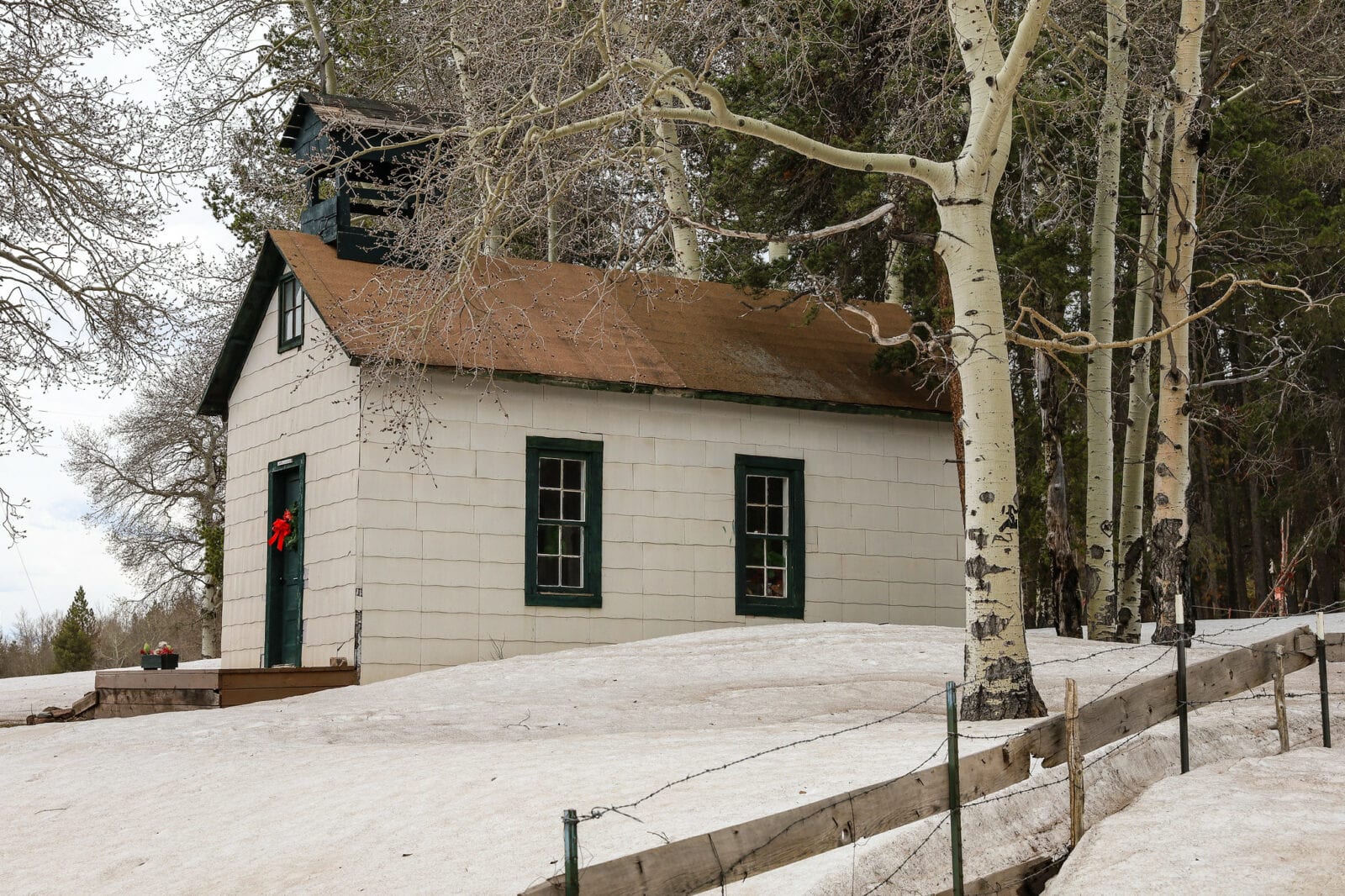 Image of a white building with a green door during winter in Uptop, Colorado