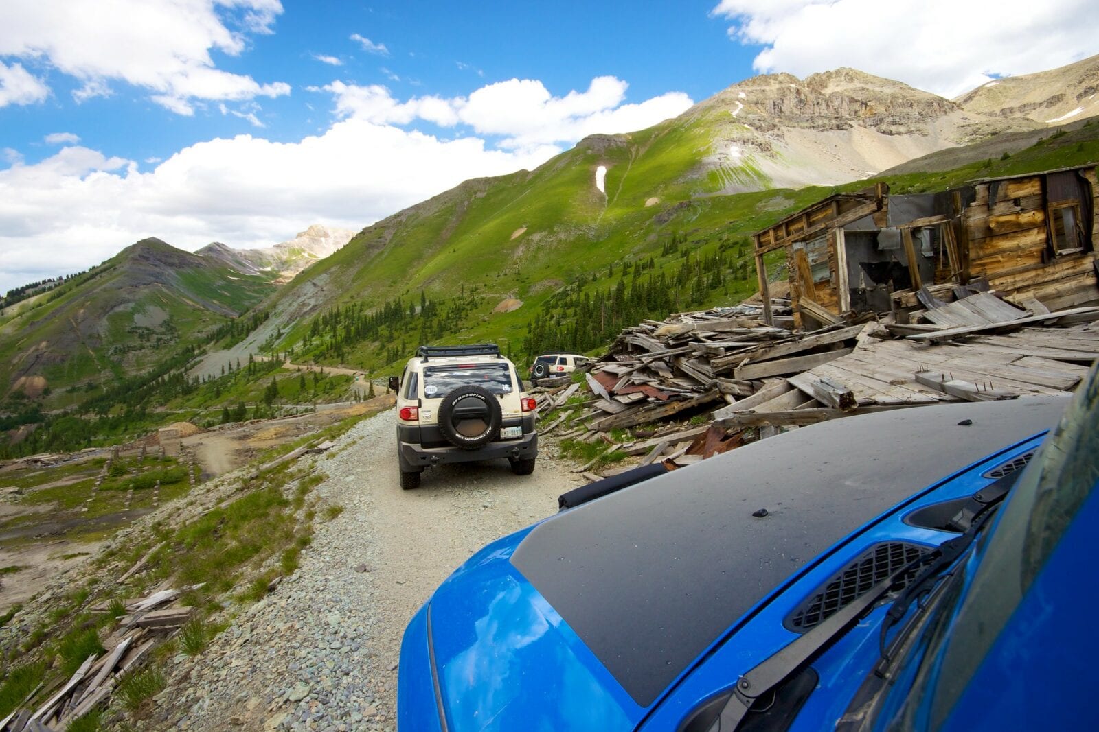 Image of cars traversing the Imogene Pass in Colorado, passing an abandoned building