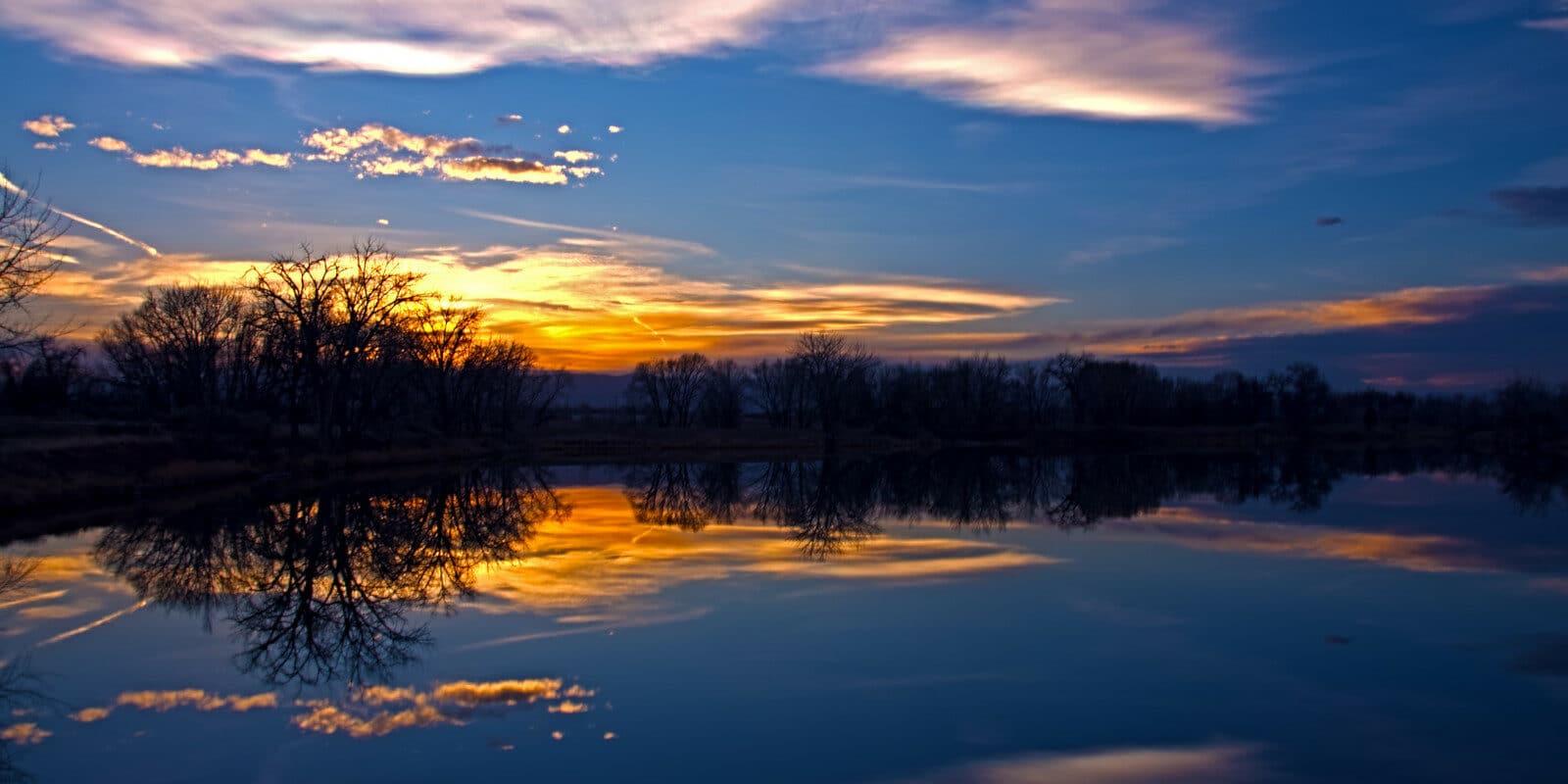 Image of the sunset reflecting on the water at at Riverbend Ponds Natural Area in Fort Collins, Colorado