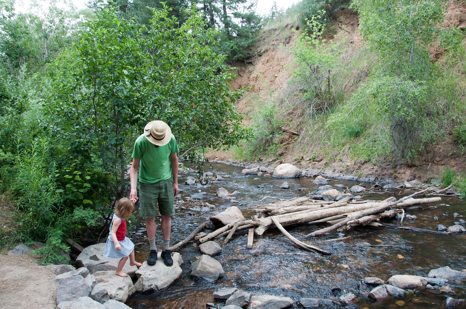 Image of a father and child crossing a creek at Lair o' the Bear Park in Idledale, Colorado