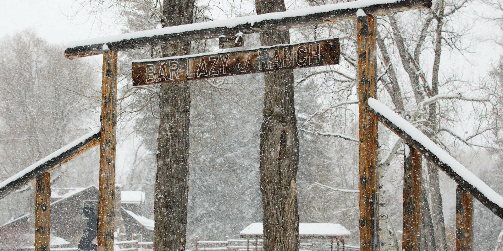 Image of the Bar Lazy J Guest Ranch entrance sign covered in snow