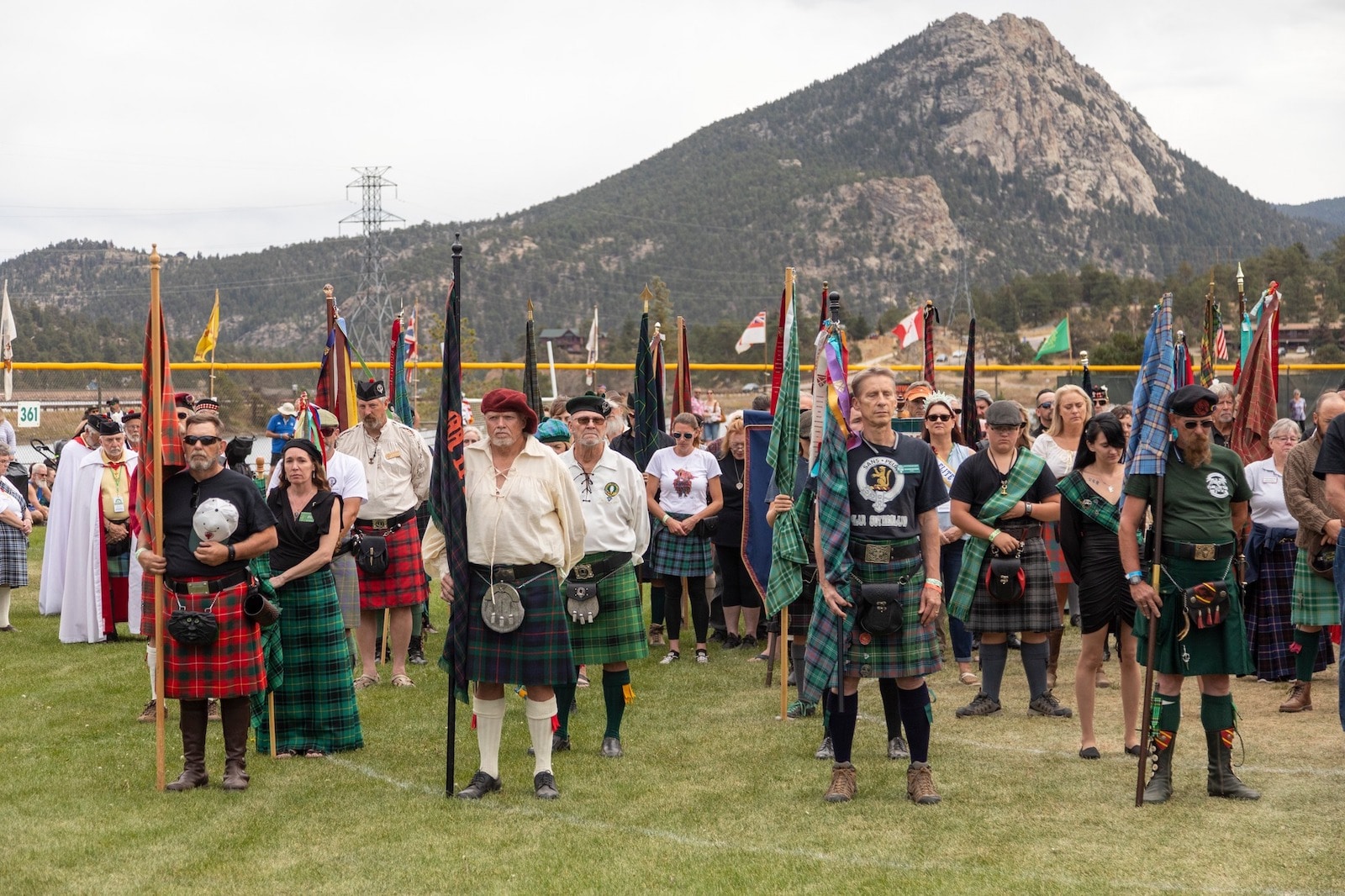 Image of people in kilts holding different flags at the Long's Peak Scottish-Irish Highland Festival in Colorado