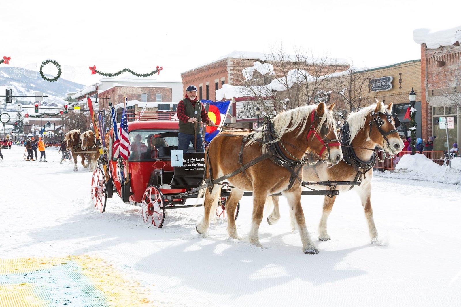 Image of a carriage being pulled by horses through snow at Steamboat Springs Winter Carnival in Colorado