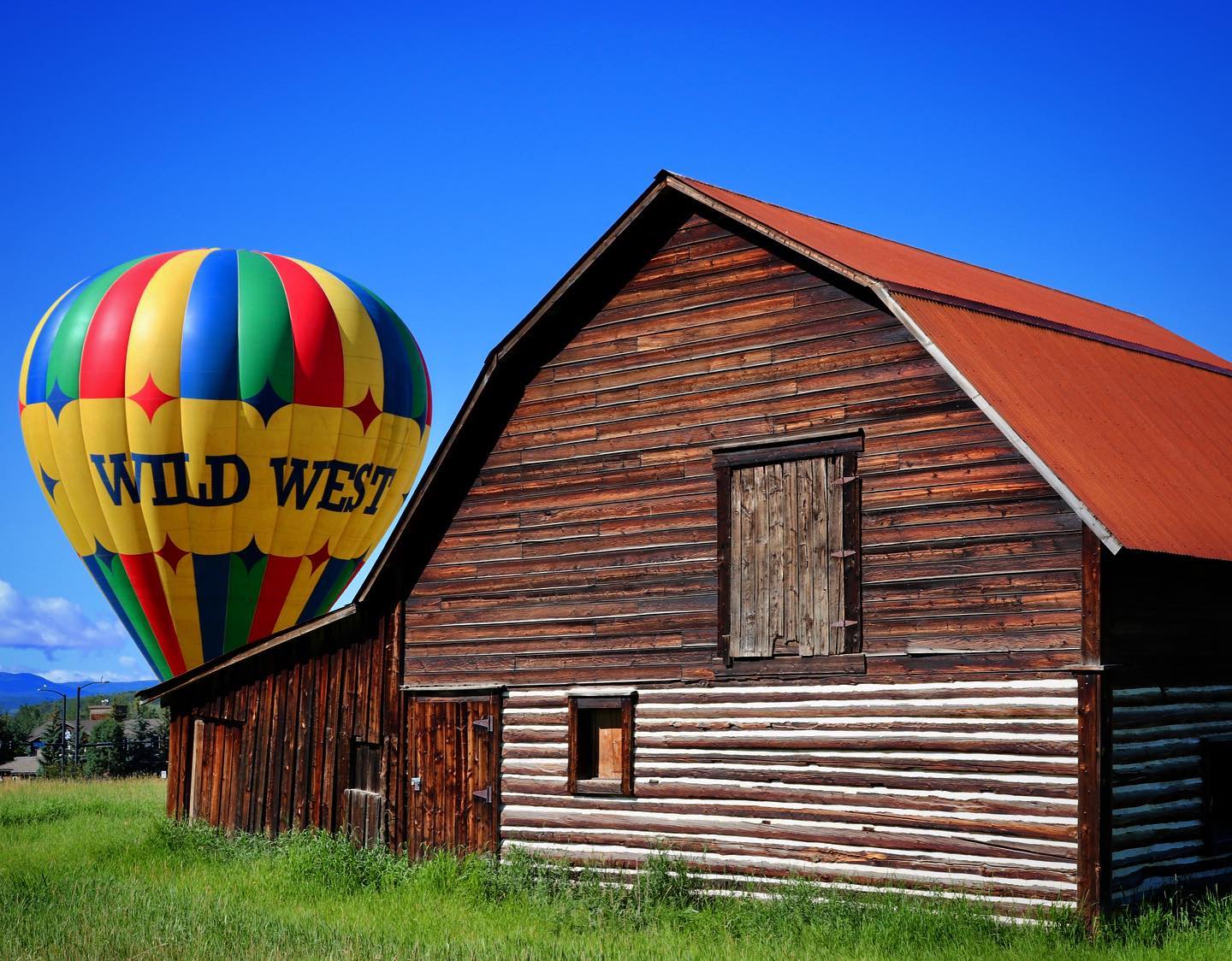 Image of the Wild West Balloon Adventures balloon behind a barn 