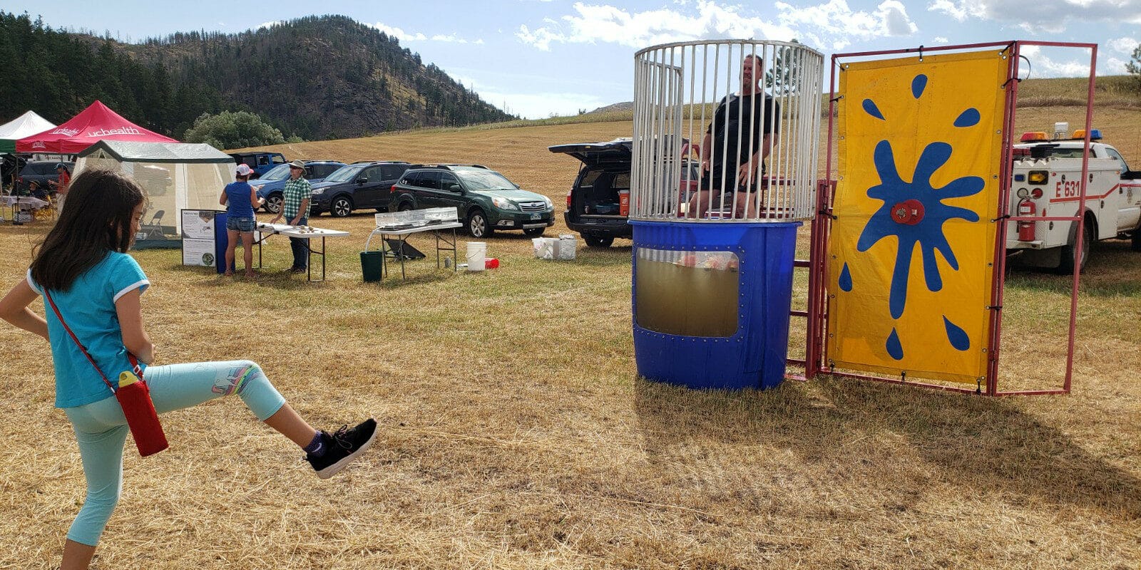 Image of a girl throwing a ball at a dunk tank at the Rist Canyon Volunteer Fire Department Mountain Festival in Bellvue, Colorado