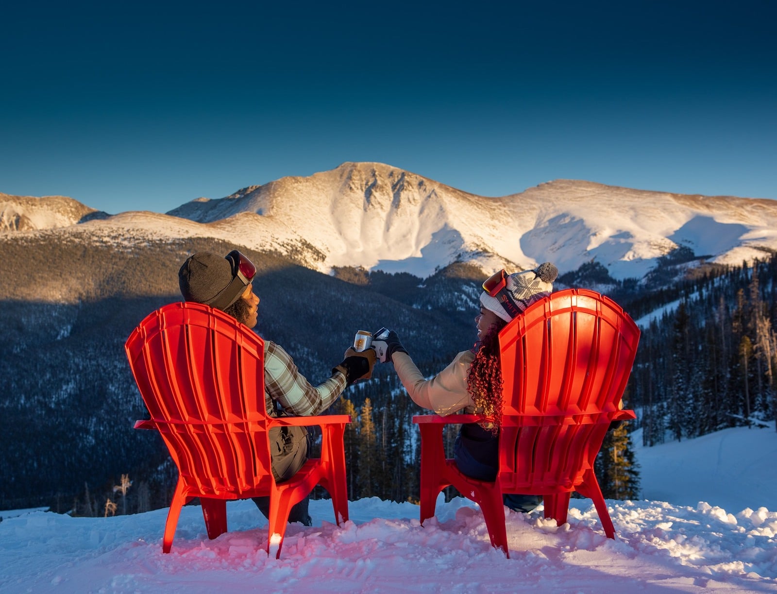 Image of people in red chairs looking out at the mountain while drinking a beer in Winter Park, Colorado