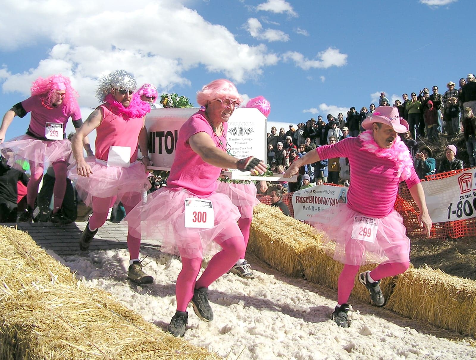 Four men in pink tutus carrying a fake coffin in a race