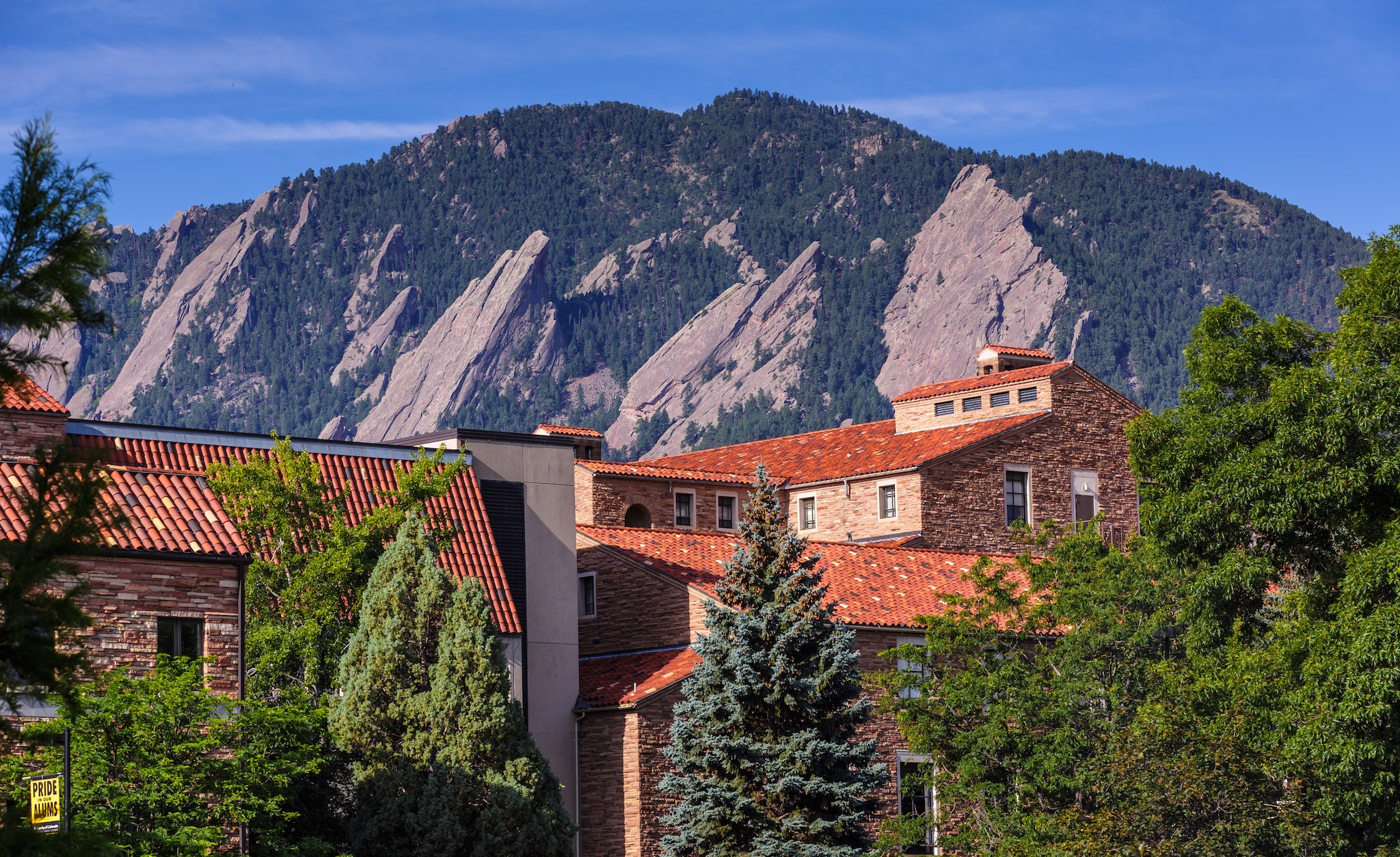 A view of CU Boulder and the iconic Flatiron rock formations behind it.