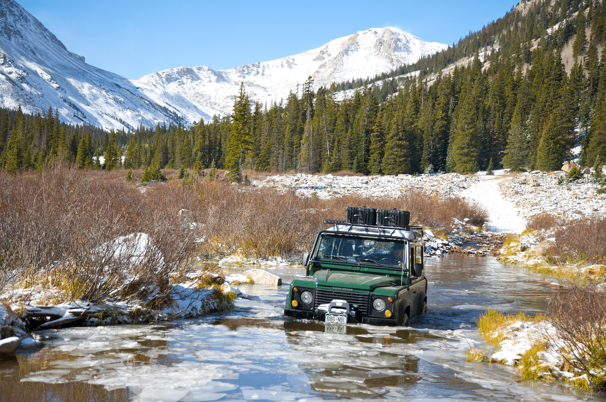 A 4WD truck crossing a deep mountain stream.