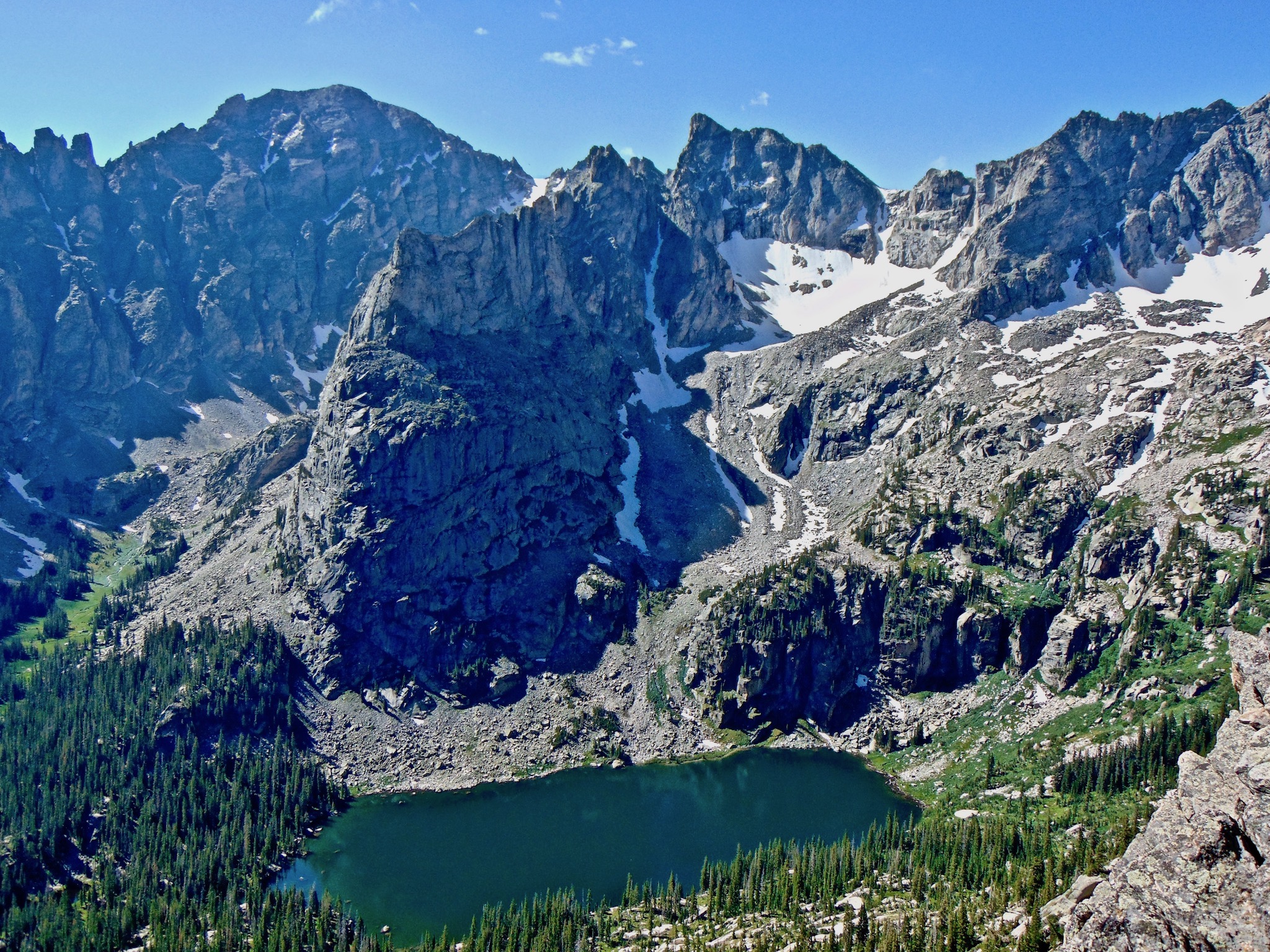 Pandangan mata burung dari danau kawah biru tua, dikelilingi oleh pegunungan terjal dari Indian Peaks Wilderness.