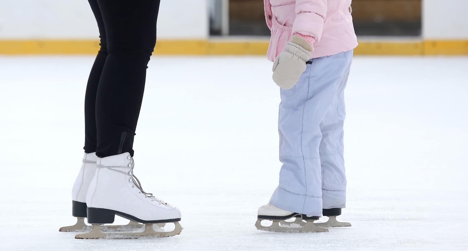 Image of the legs of two skaters on the ice at Edge Ice Arena in Littleton, Colorado