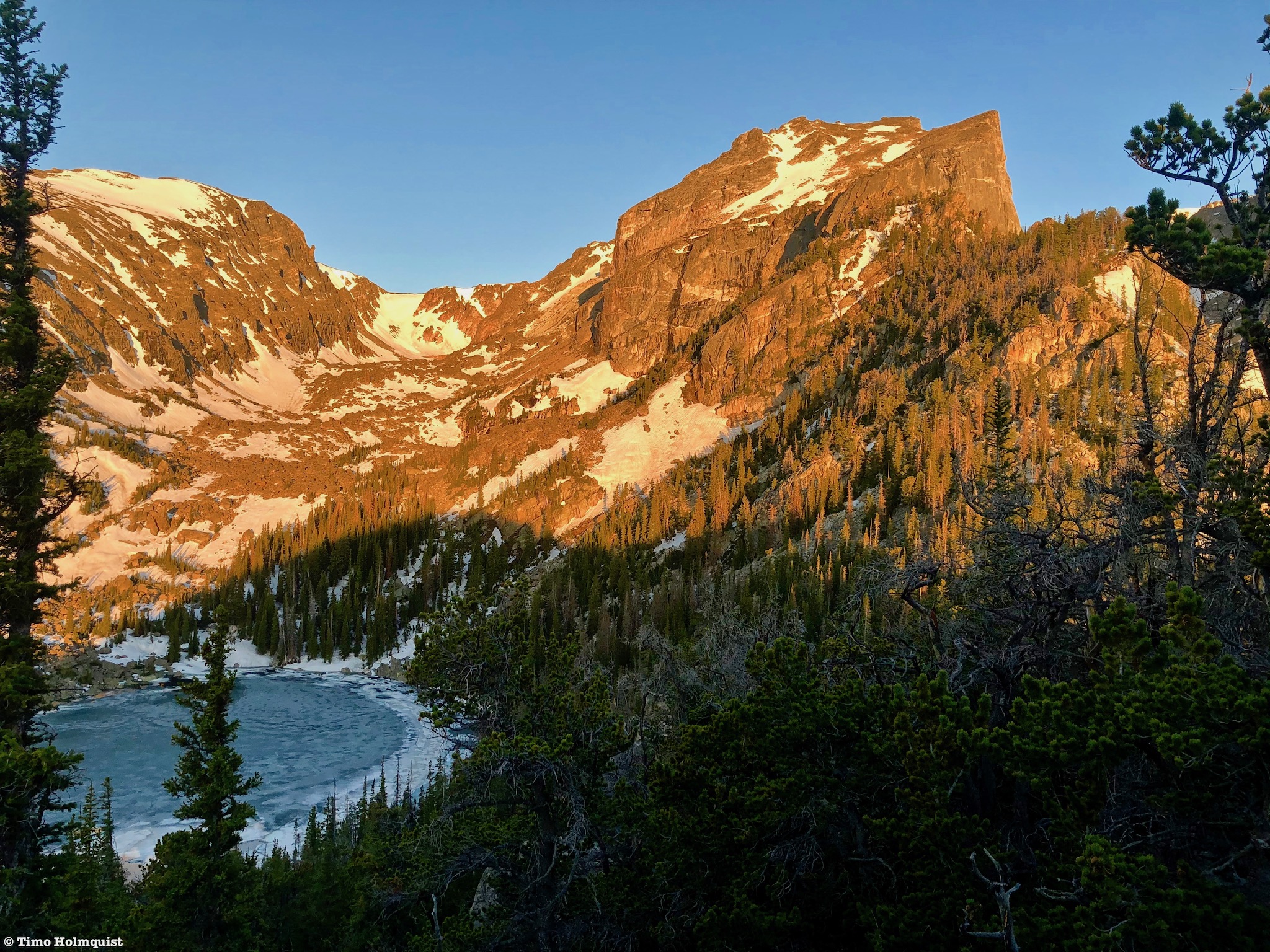 Alpenglow on Hallett Peak with a frozen Lake Haiyaha below.