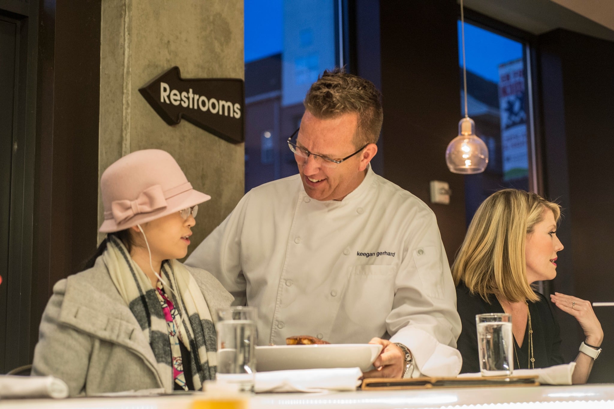 Chef speaking to a guest while he serves her a dish