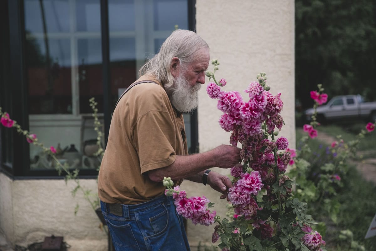 older man smells flowers in Saguache, CO