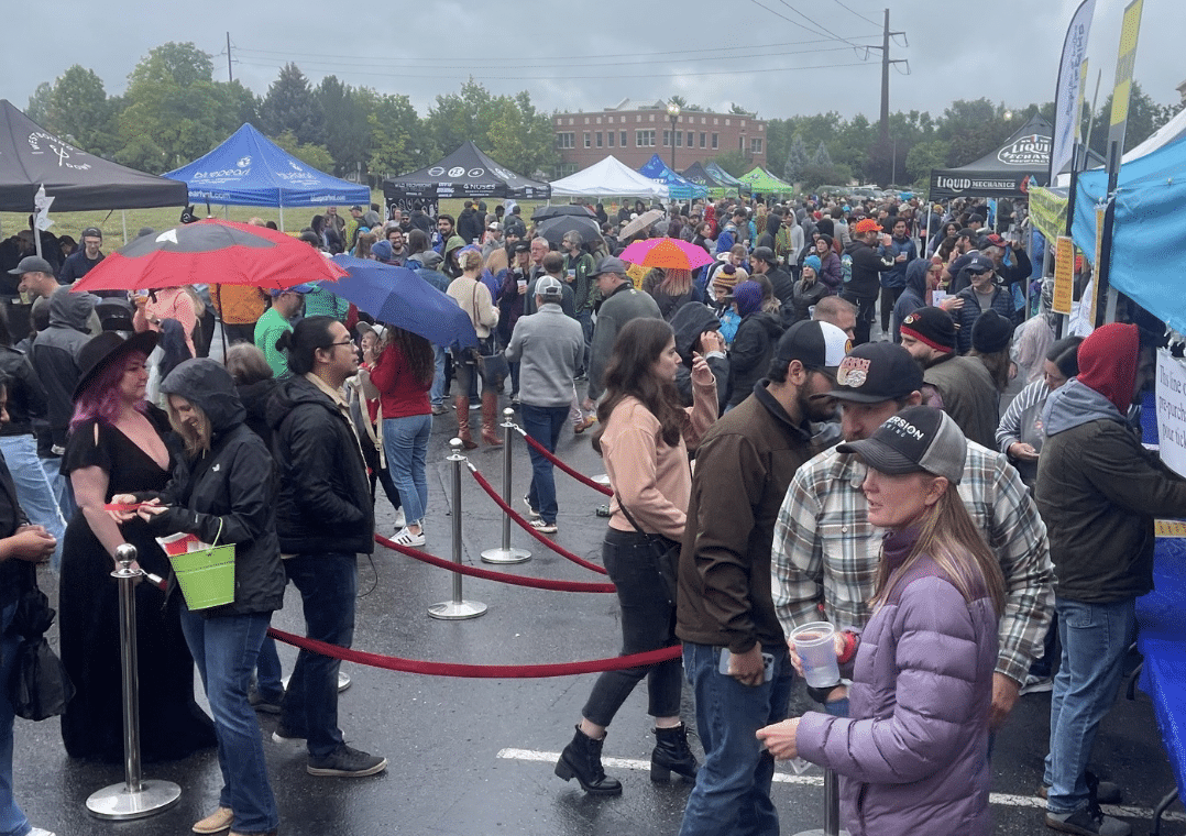 Crowd of people mingling outdoors at the Lafayette Brew Fest in the rain 