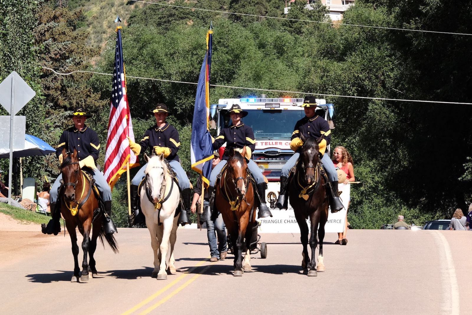 Image of people on horses carrying flags in the Bronc Day Parade in Green Mountain Falls in Colorado