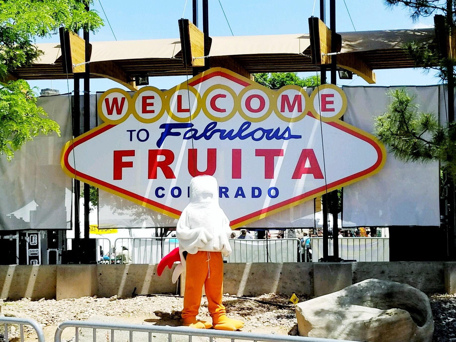 Headless chicken mascot in front of "Welcome to fabulous Fruita" sign