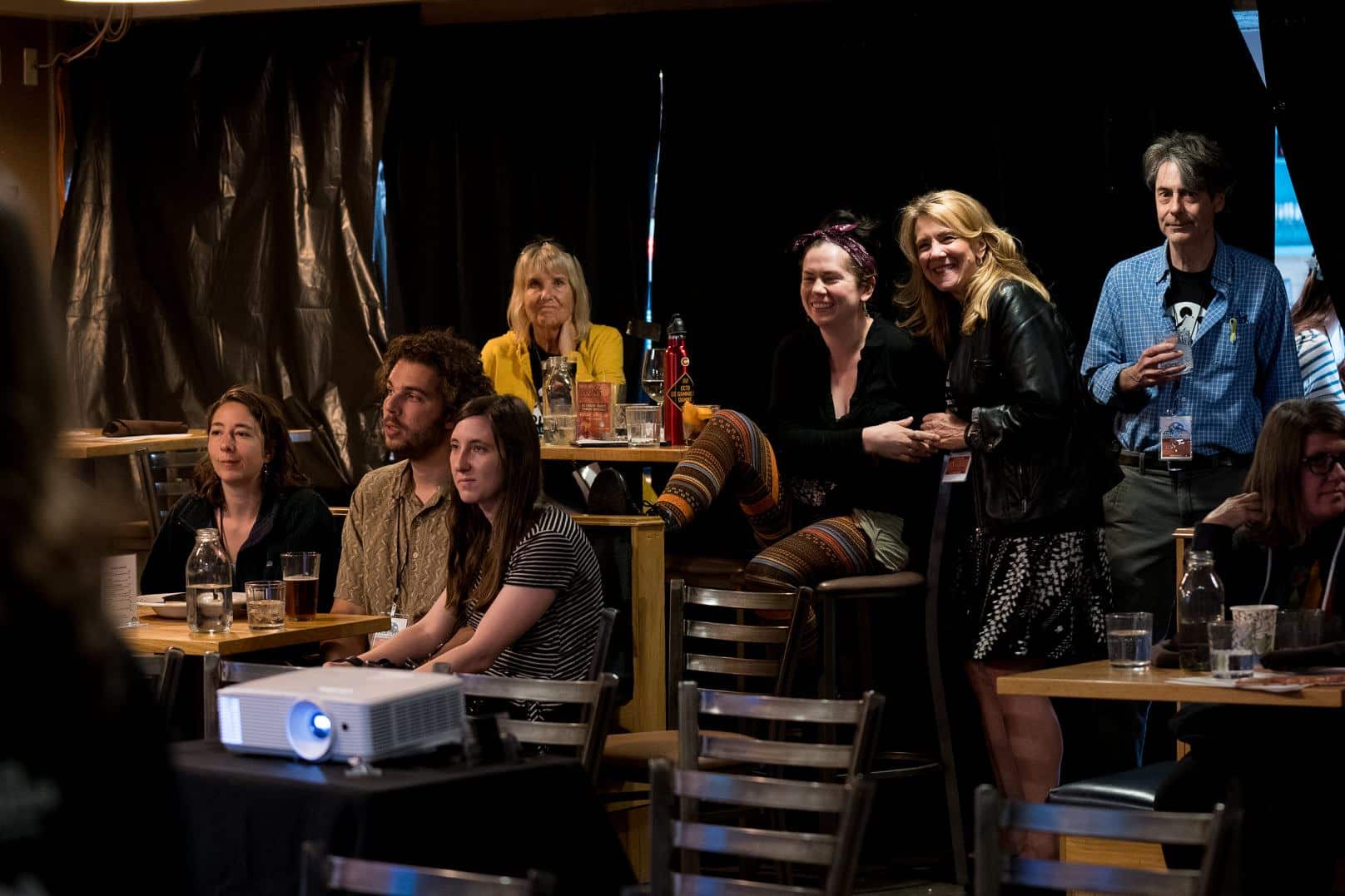 Small crowd of people in a restaurant watching a short film as part of a festival
