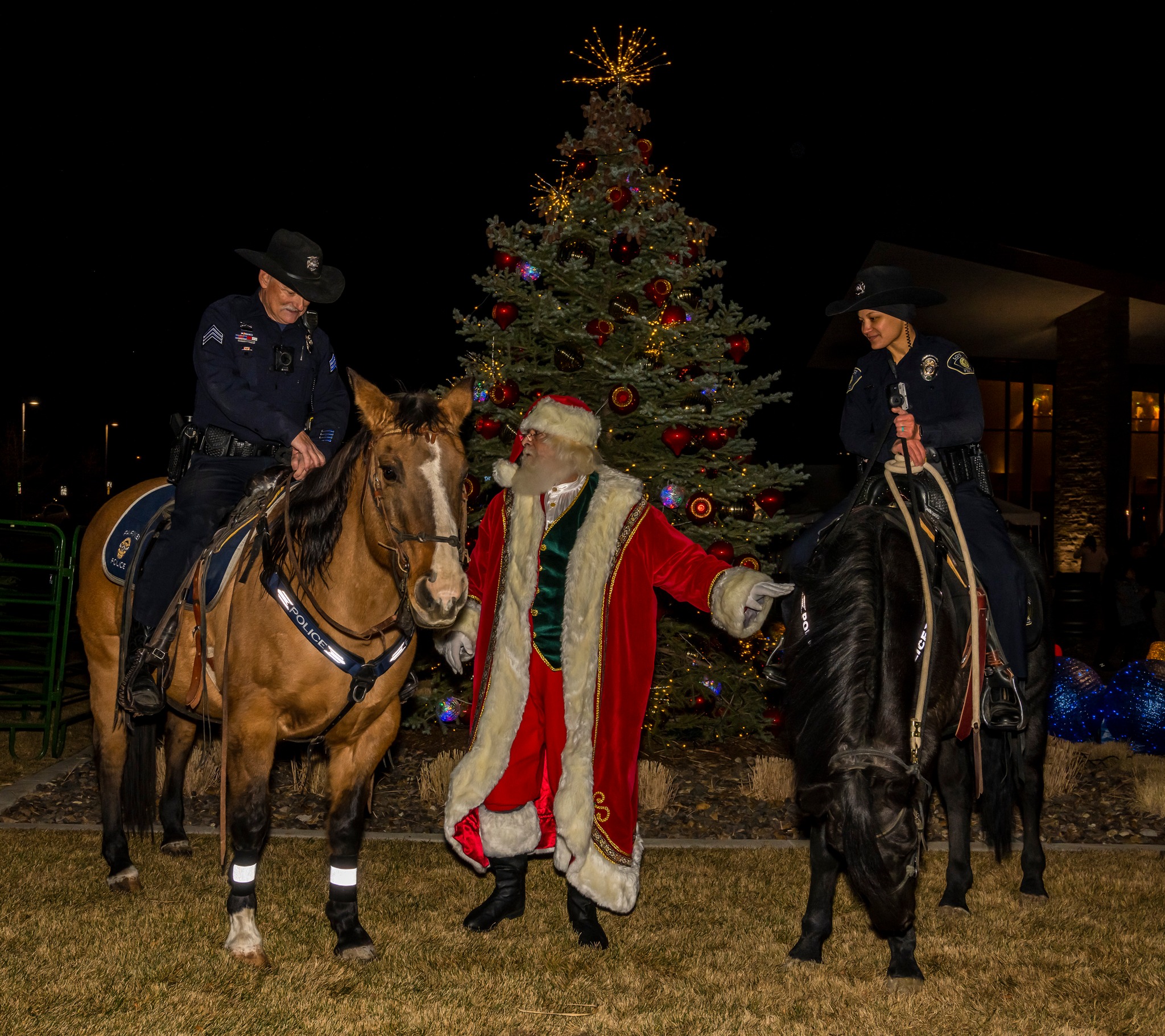 Santa standing inbetween two cops on horses