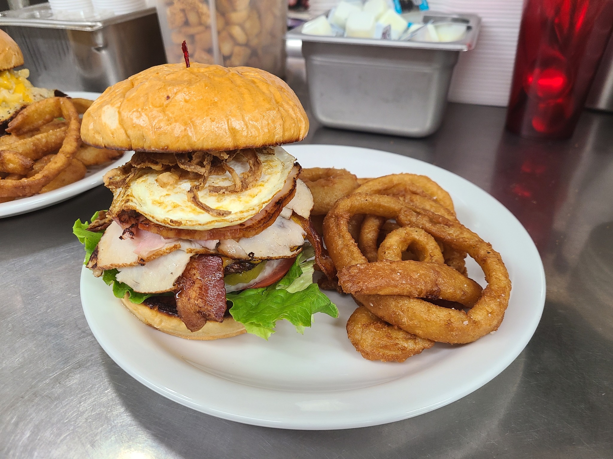 Burger with onion rings on white plate