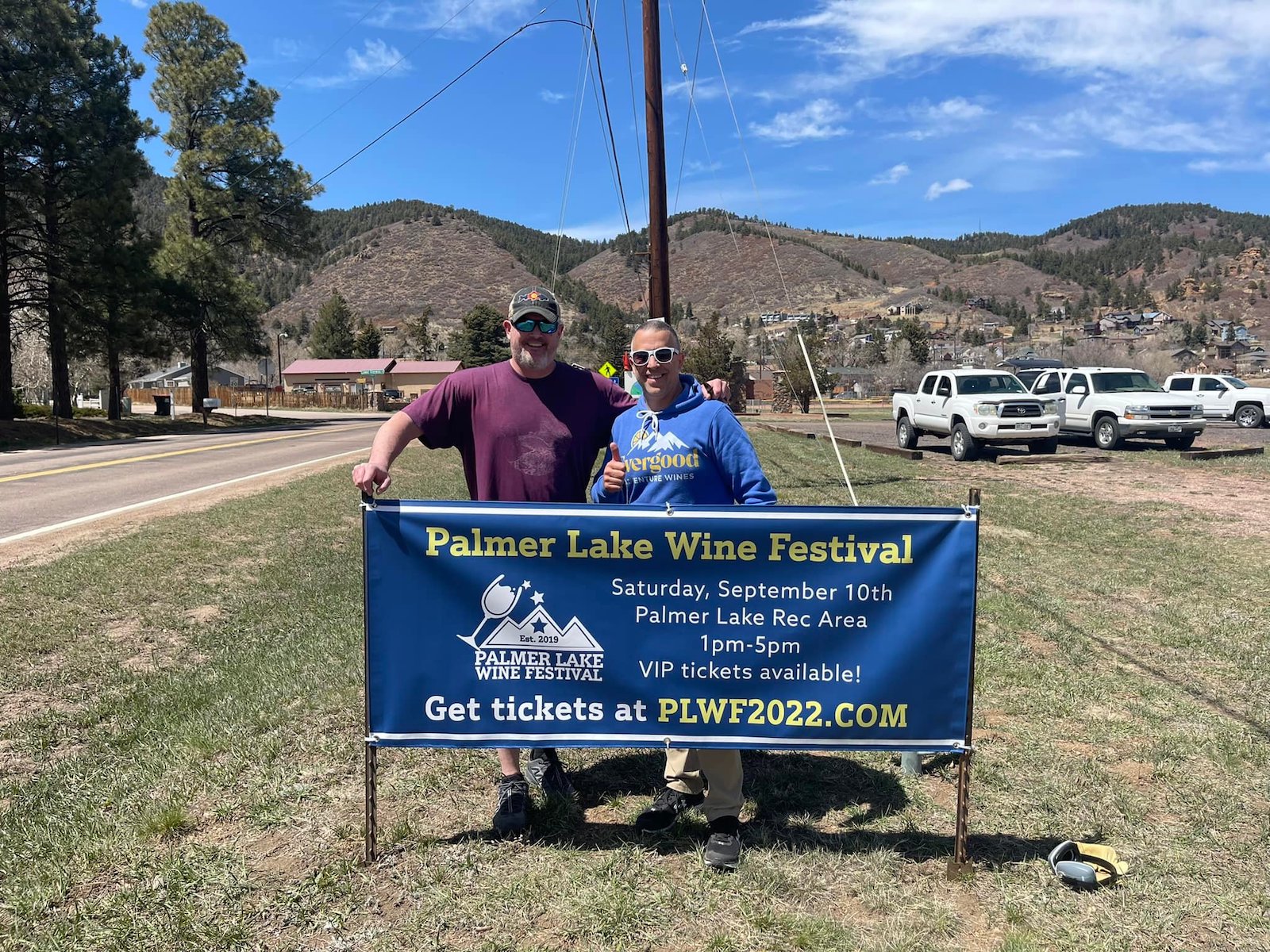 Image of two people putting up a sign for the 2022 Palmer Lake Wine Festival in Colorado