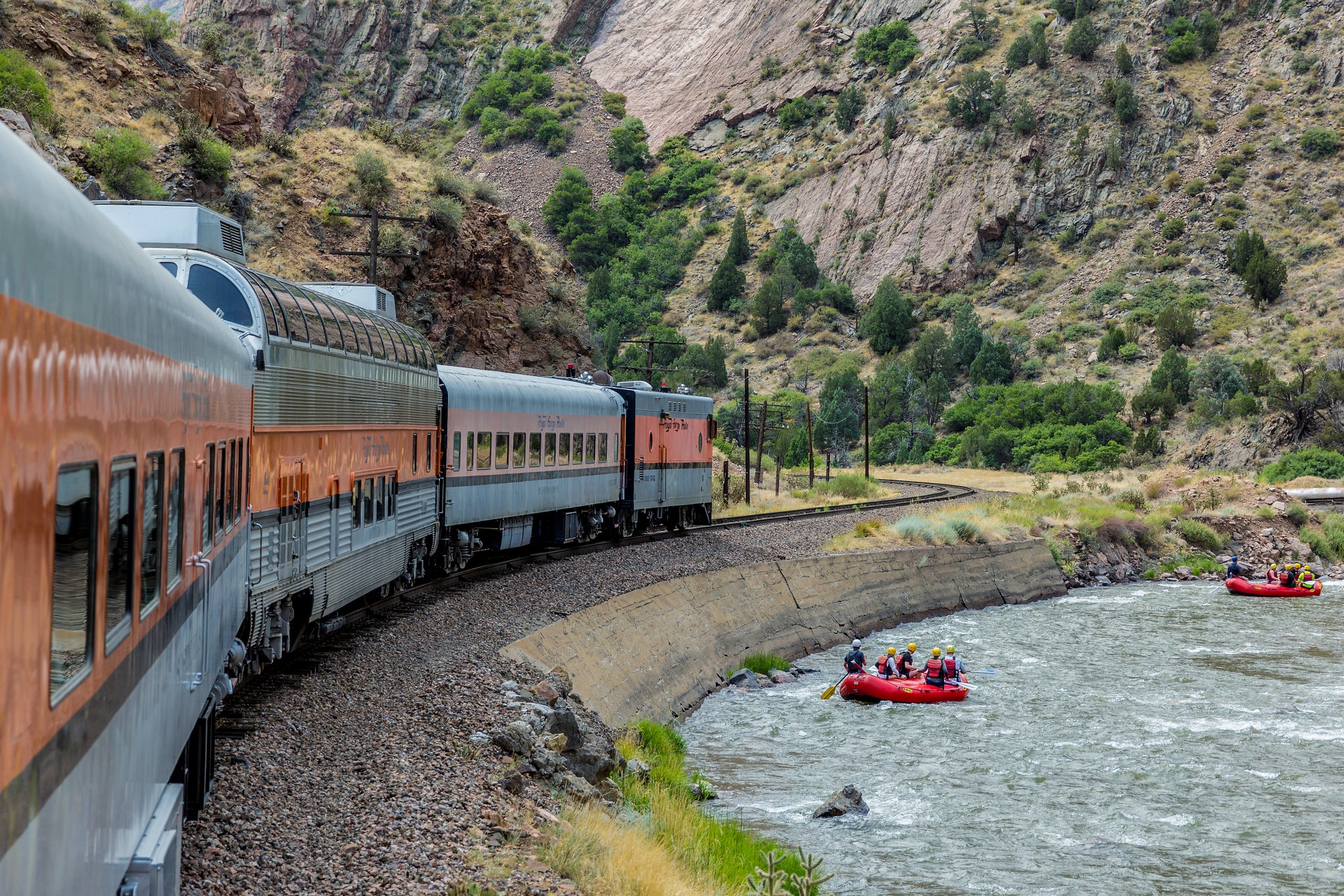 Scenic train along river with rafters