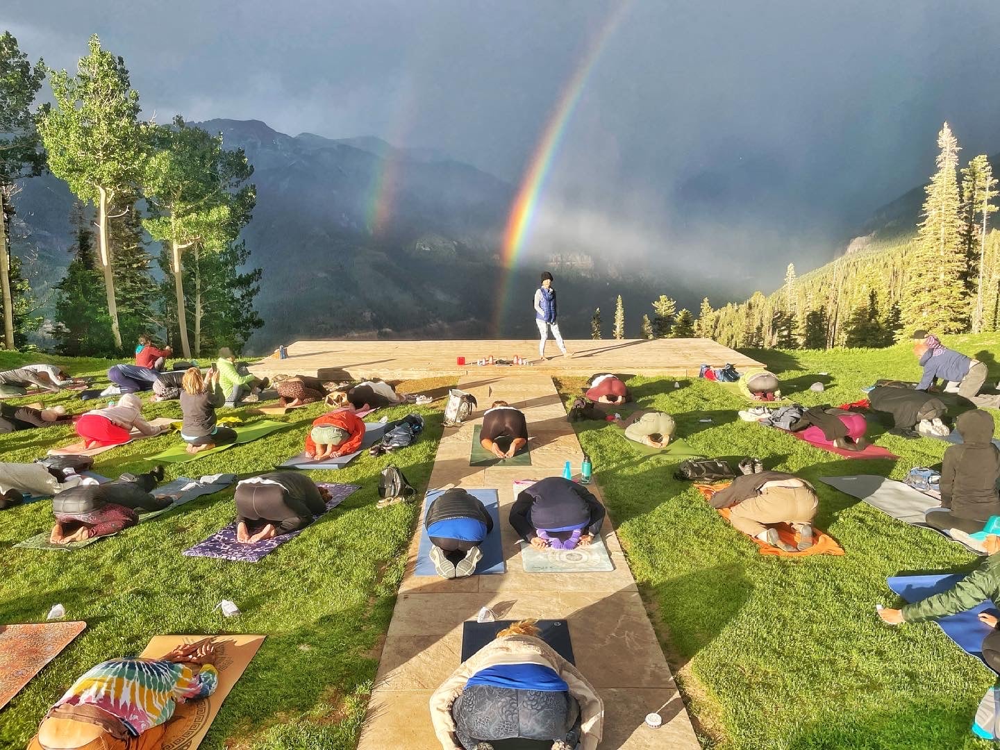 Outdoor yoga class with rainbow and mountains in the background