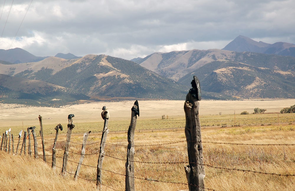 Wooden fence in front of field with mountains