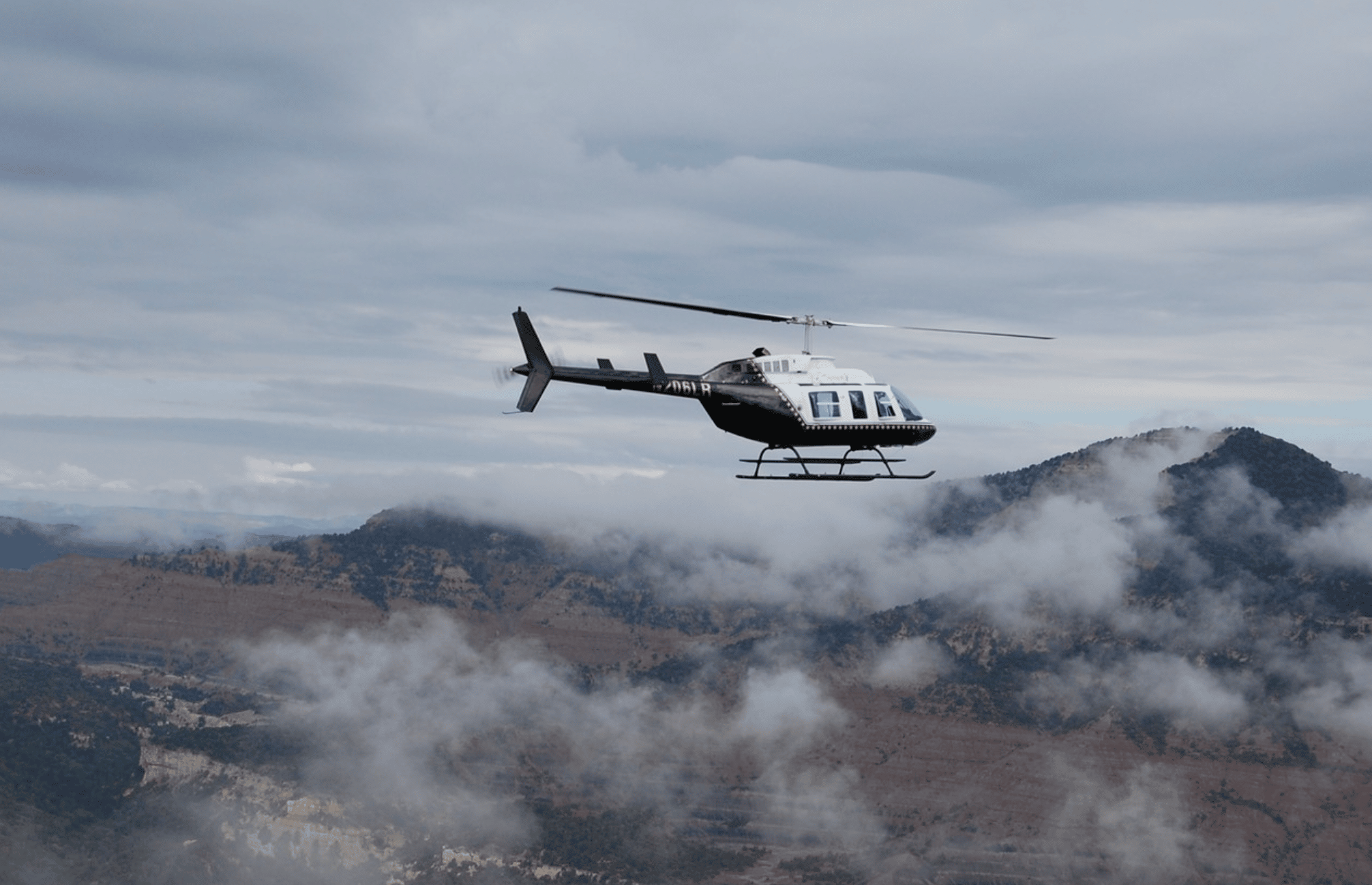 Helicopter in cloudy sky over mountains