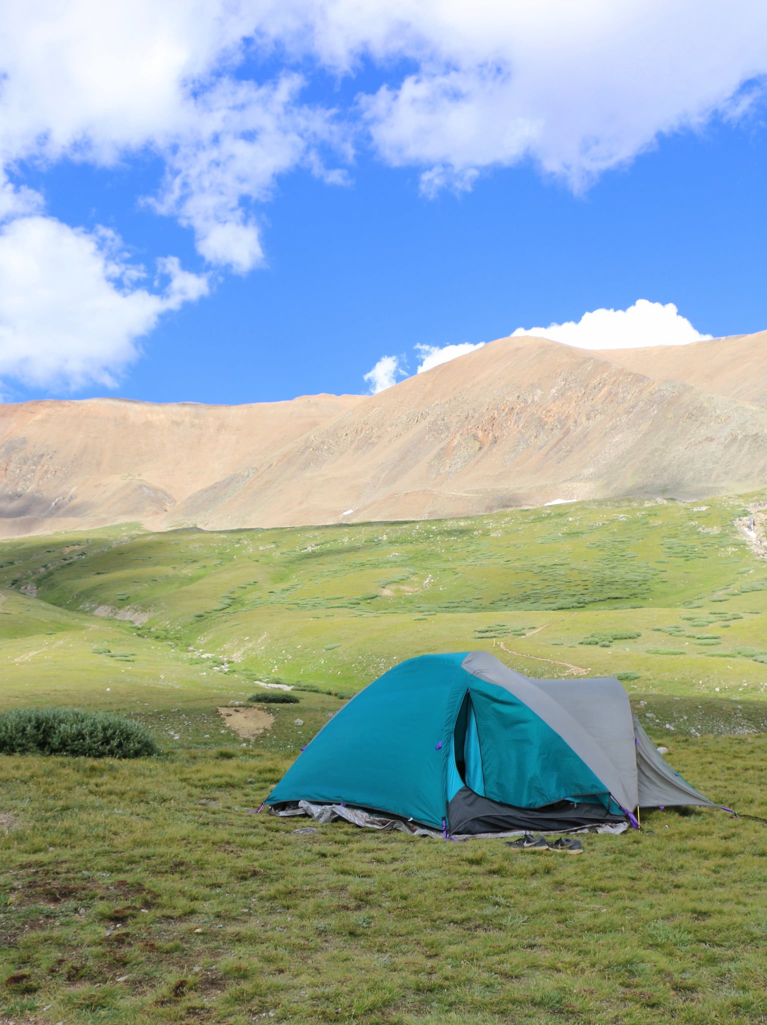 Blue tent on a green field in the mountains