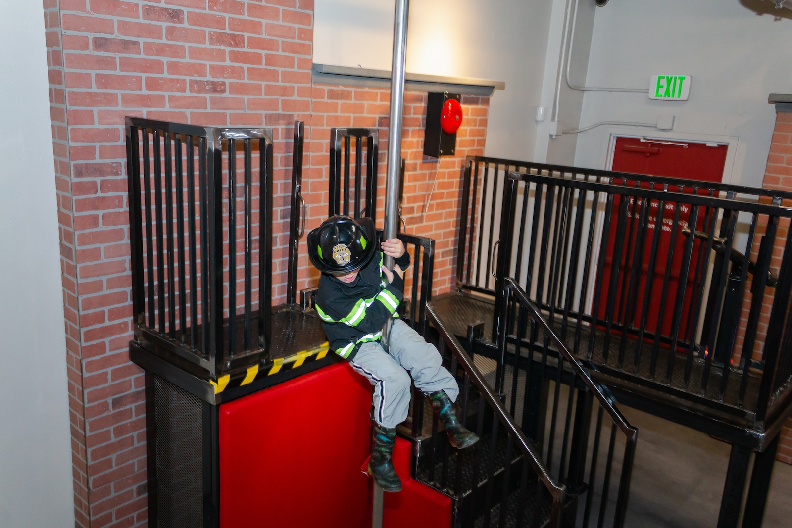 Image of a child sliding down a fire pole at the Fire Station No 1 area in the Imagination exhibit at the Children's Museum of Denver Marsico Campus