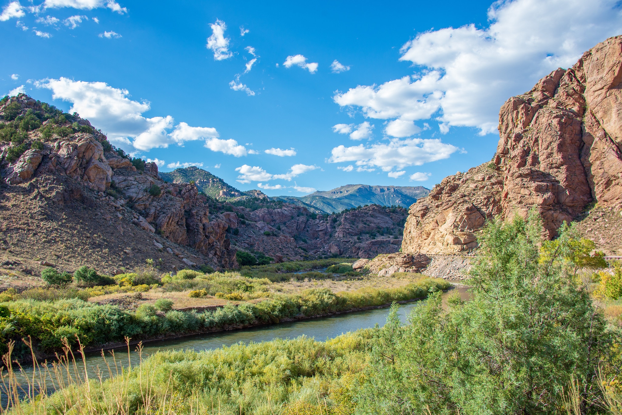 Blue skies over a river running through a rock canyon