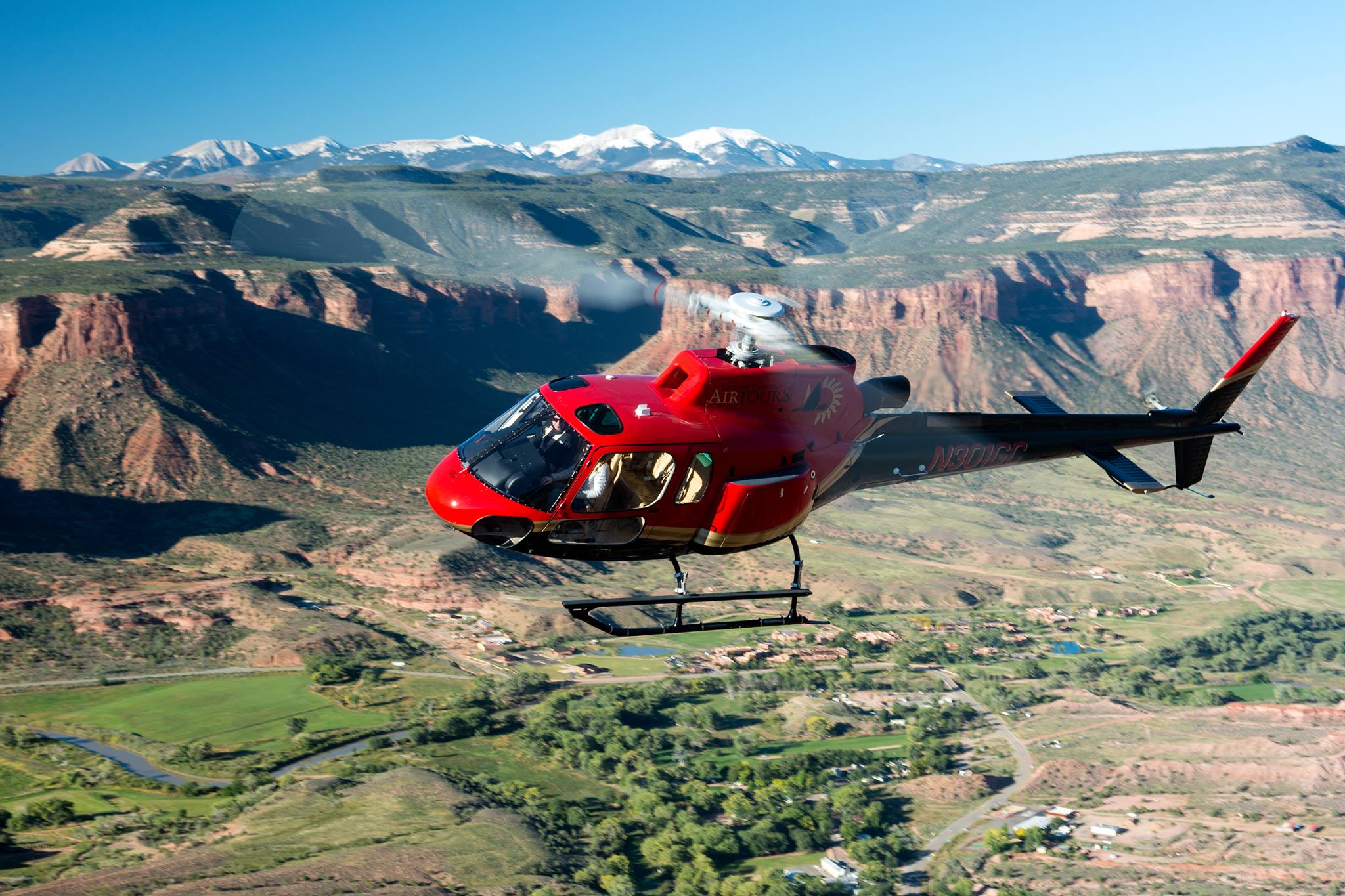 Red helicopter in flight over canyons