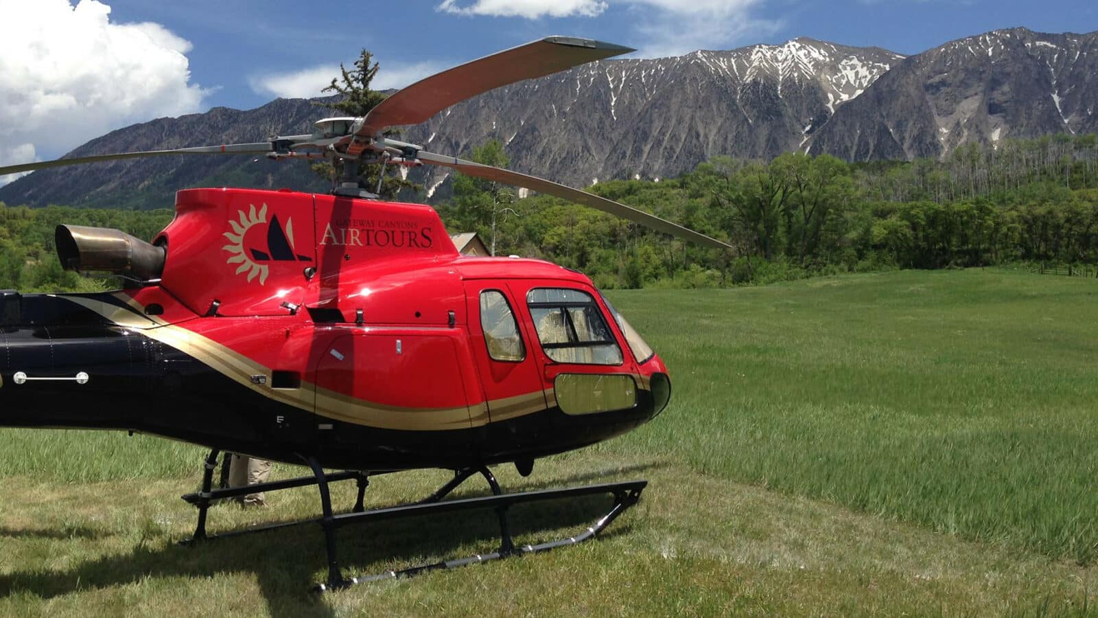 Red helicopter in field with mountains in the back