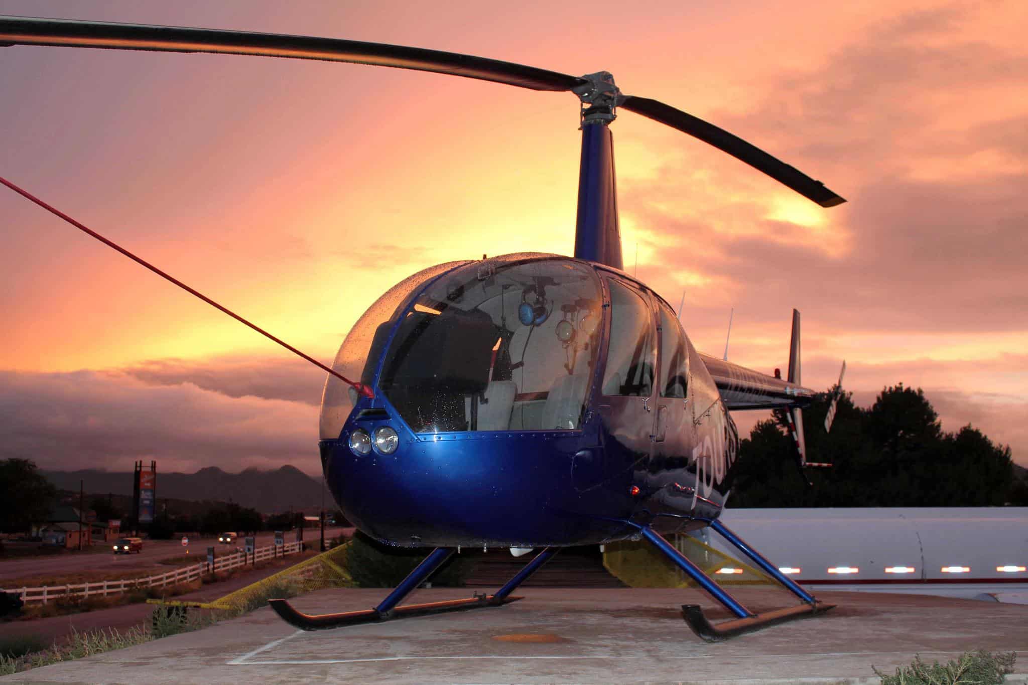 Blue helicopter on a landing pad with sunset in the background