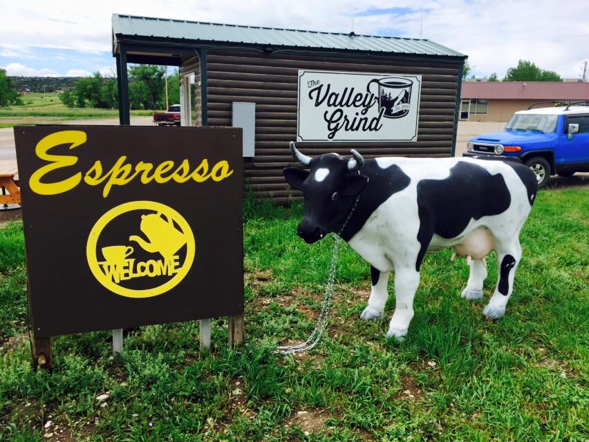 Fake cow outside of a small coffee stand