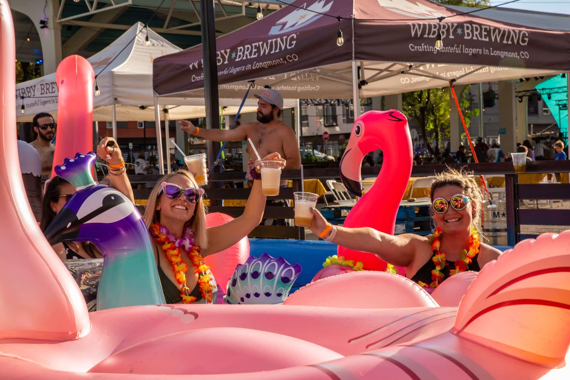 Two people in pool floaties with beer