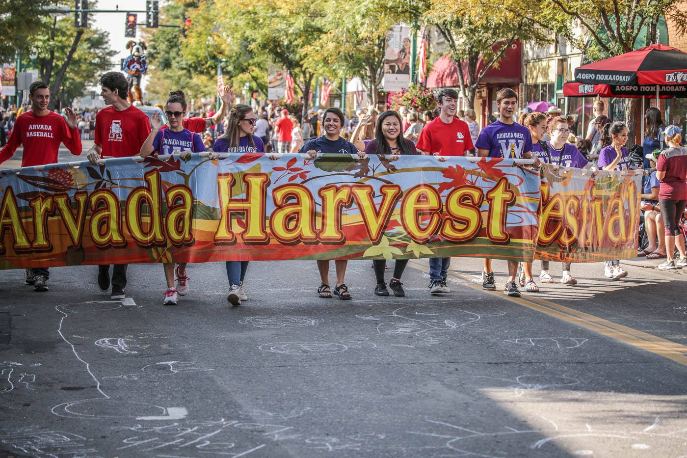 People in parade holding "Arvada Harvest Festival" banner