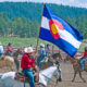 Cowboy holding a Colorado state flag at a rodeo in Pagosa Springs