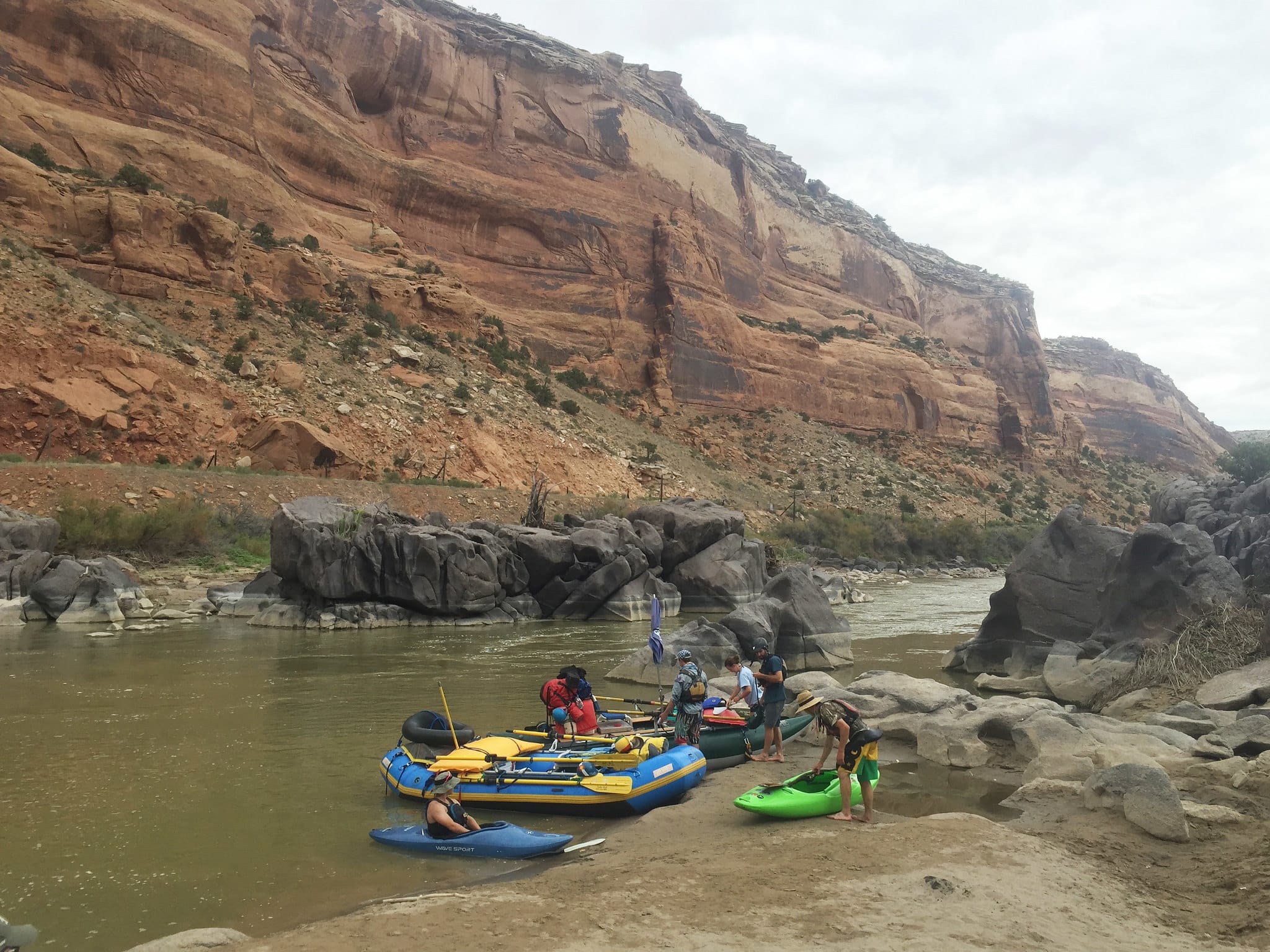 Red rock canyon over river with tubers on the shore