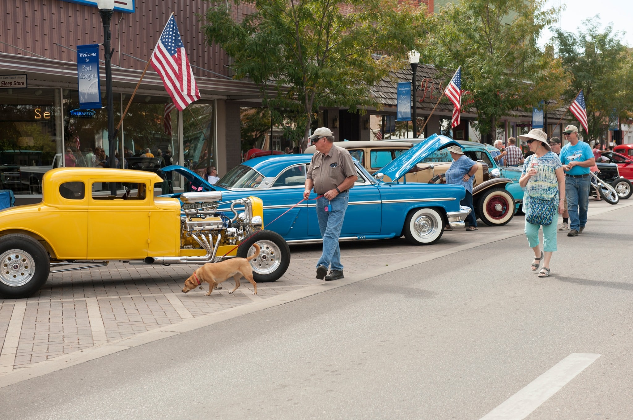 Couple walking their dog through a car show