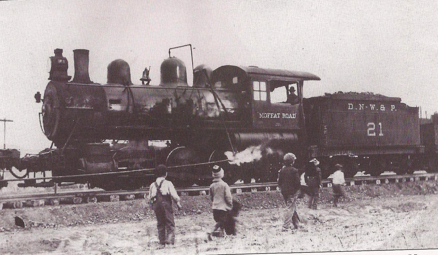 Black and white picture of railcar with children watching on