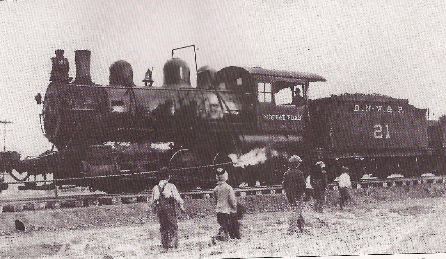 Black and white picture of railcar with children watching on