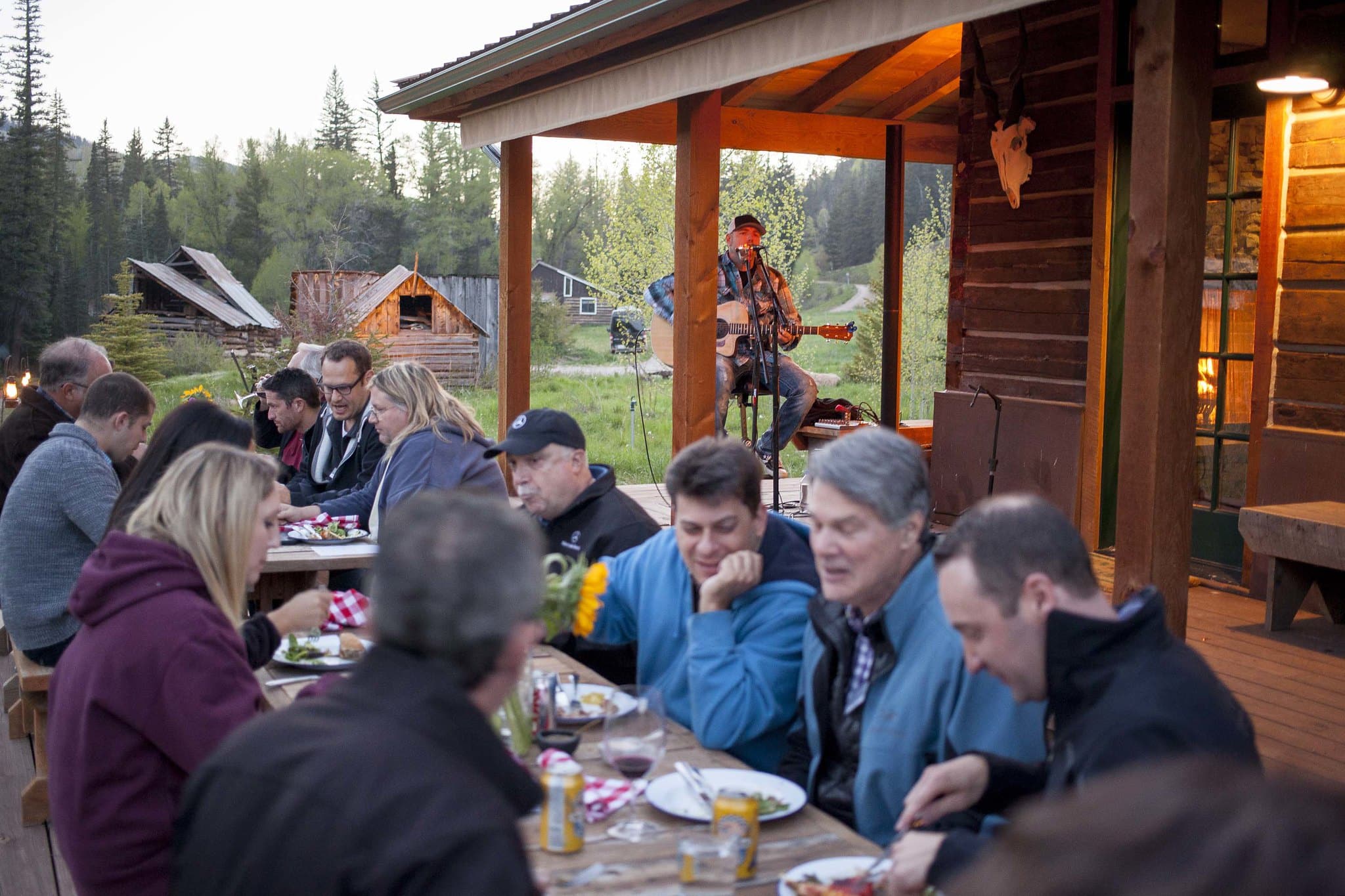 Group of people eating at a long dining table outside