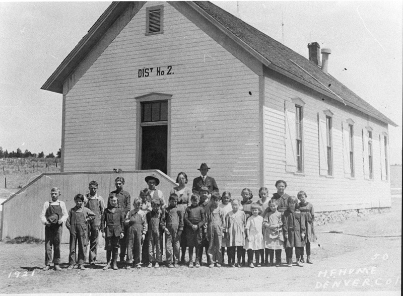 Black and white picture of historic school building with children standing in front